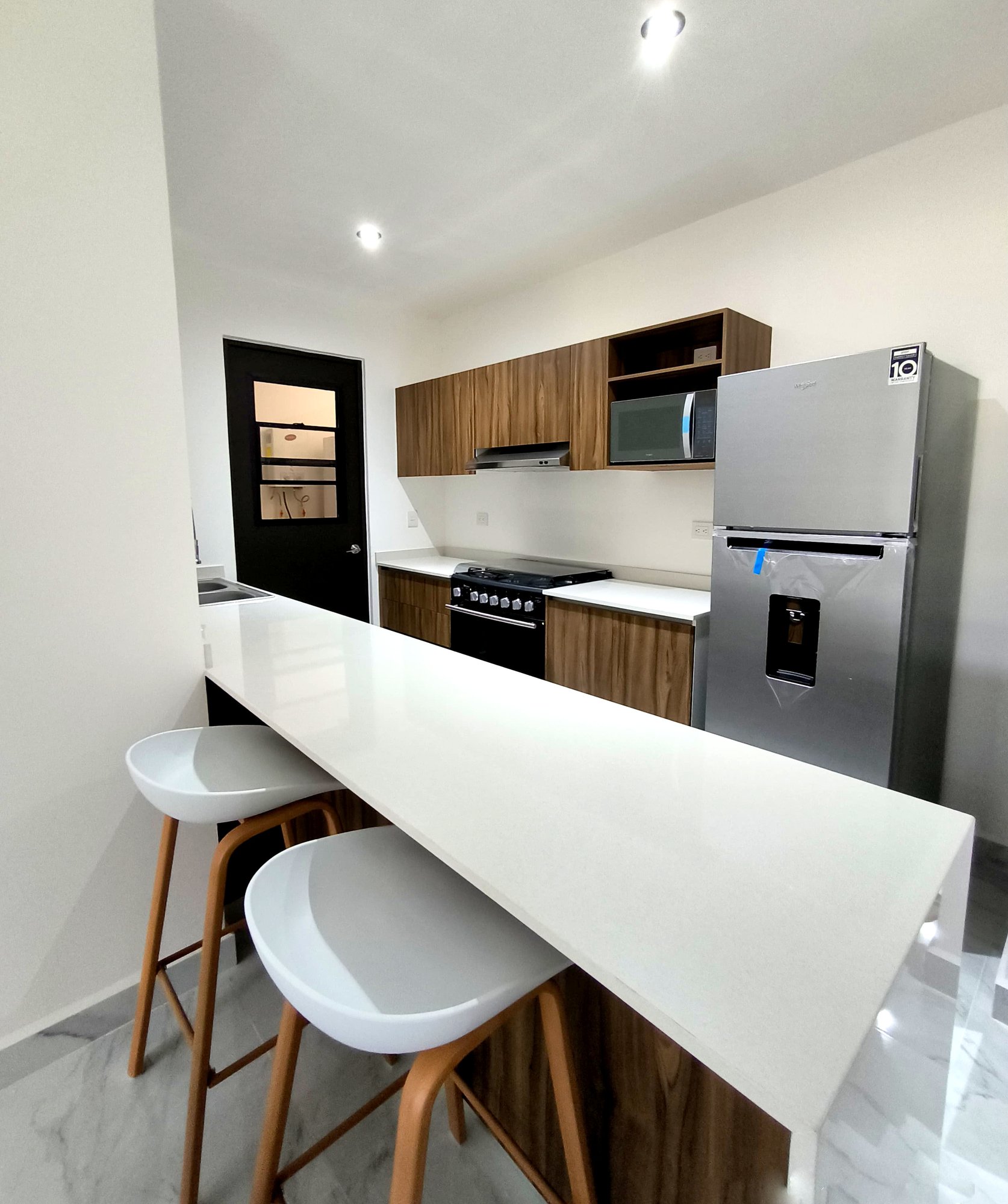 Stylish kitchen with breakfast bar and modern appliances in a furnished apartment for rent in Playa del Carmen – La Selva Residences