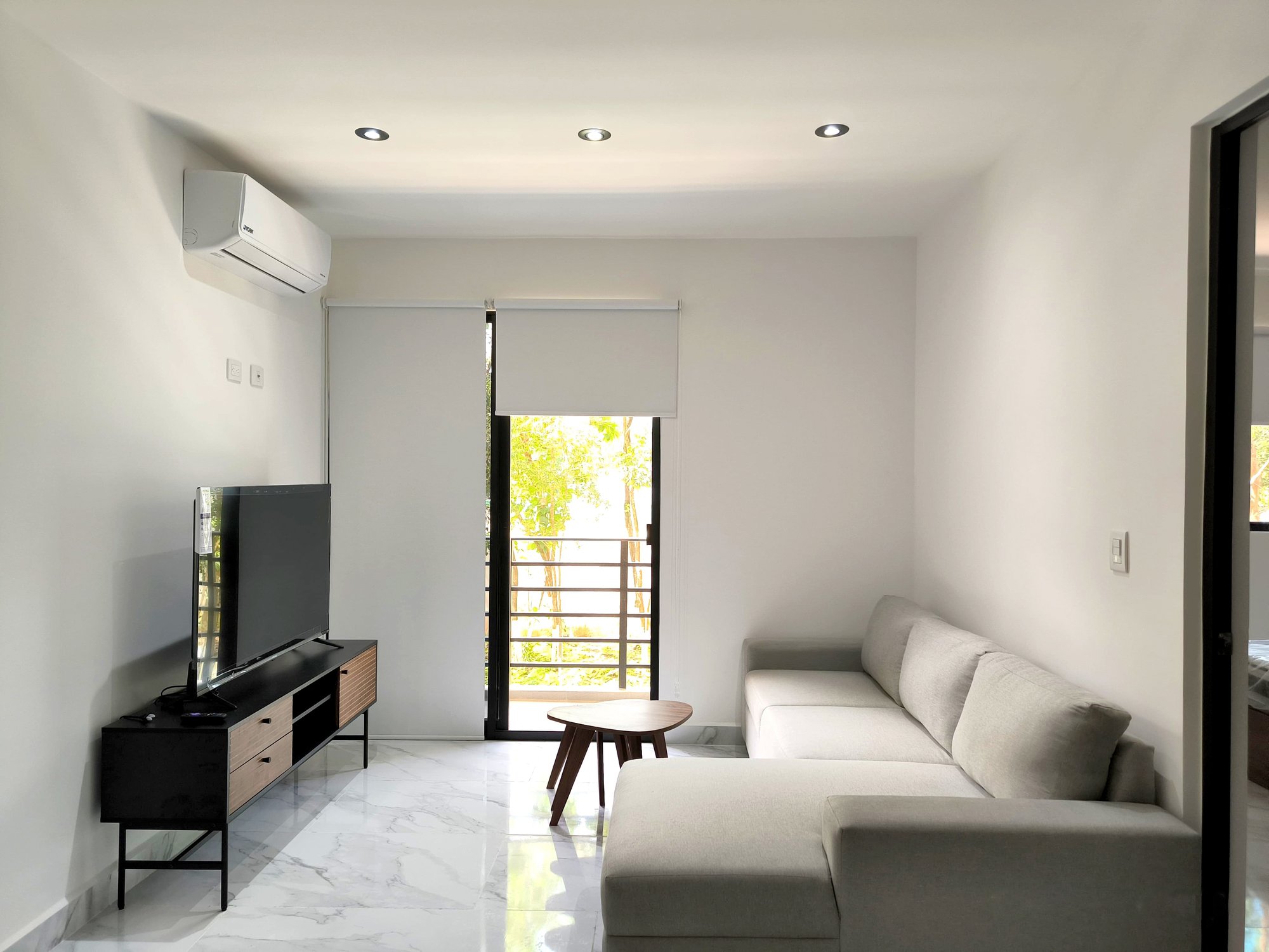 Cozy and modern living room with balcony and TV in a furnished apartment for rent in Playa del Carmen – La Selva Residences
