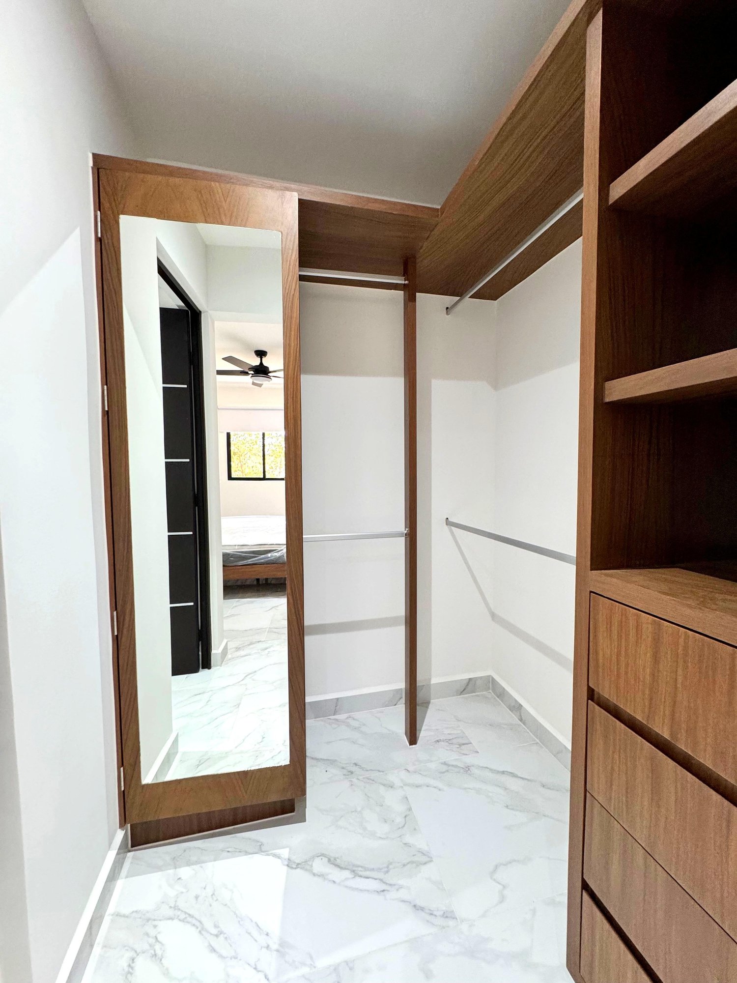 Spacious walk-in closet with wooden shelves and full-length mirror in a furnished apartment for rent in Playa del Carmen – La Selva Residences
