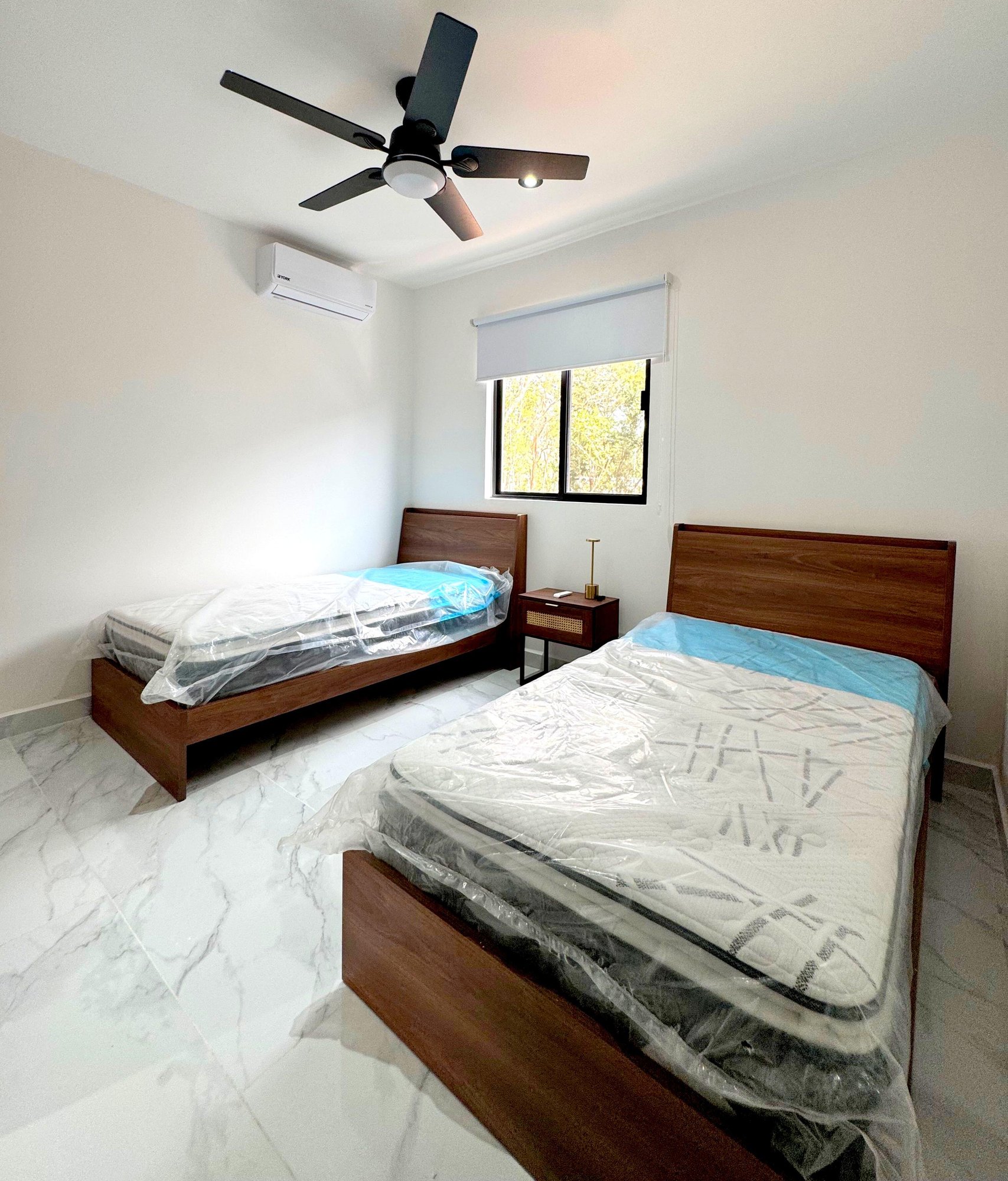 Bright secondary bedroom with two beds and large windows in a furnished apartment for rent in Playa del Carmen – La Selva Residences