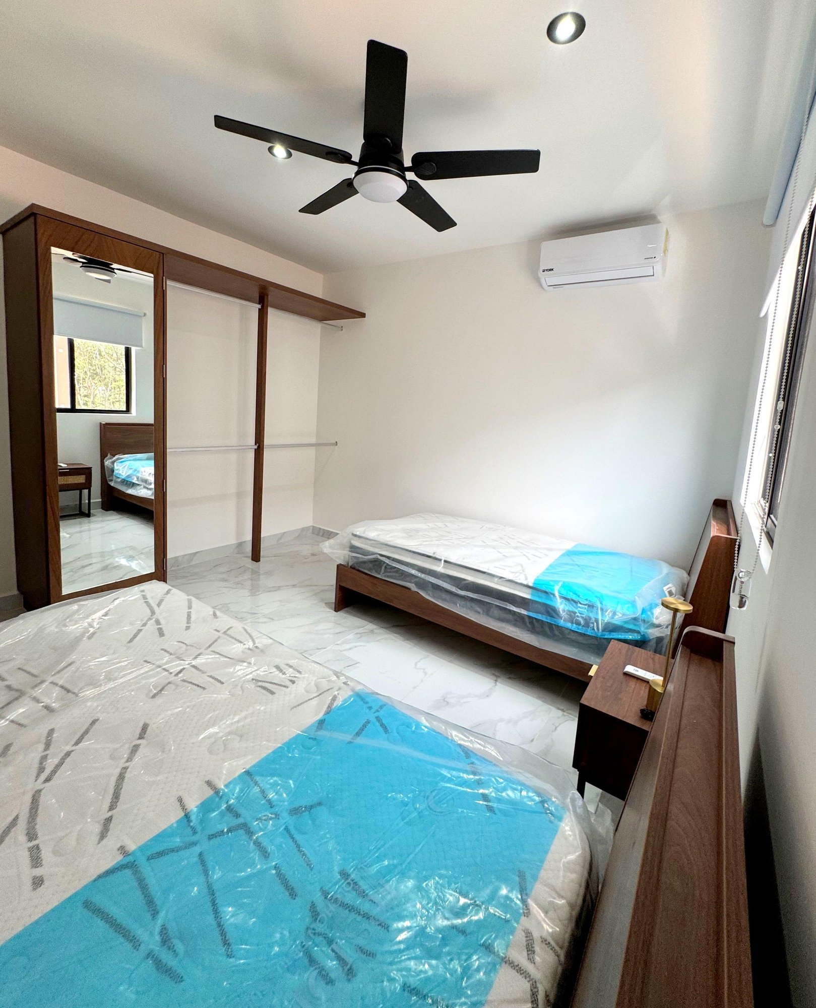 Spacious secondary bedroom with two beds, built-in closet, and natural lighting in a furnished apartment for rent in Playa del Carmen – La Selva Residences