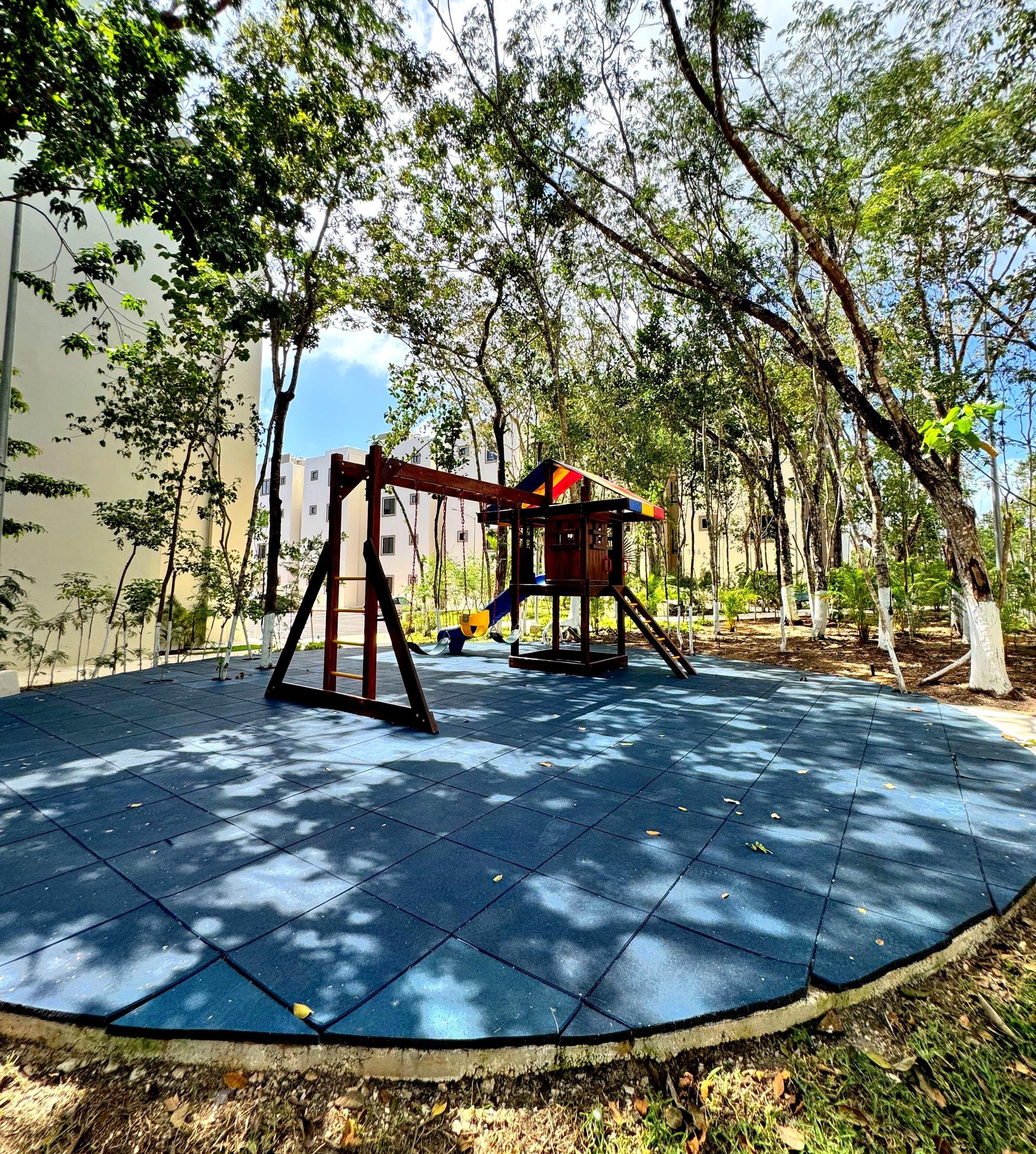 Kids playground with swings and playhouse surrounded by nature at La Selva Residences – Family-friendly amenities in Playa del Carmen