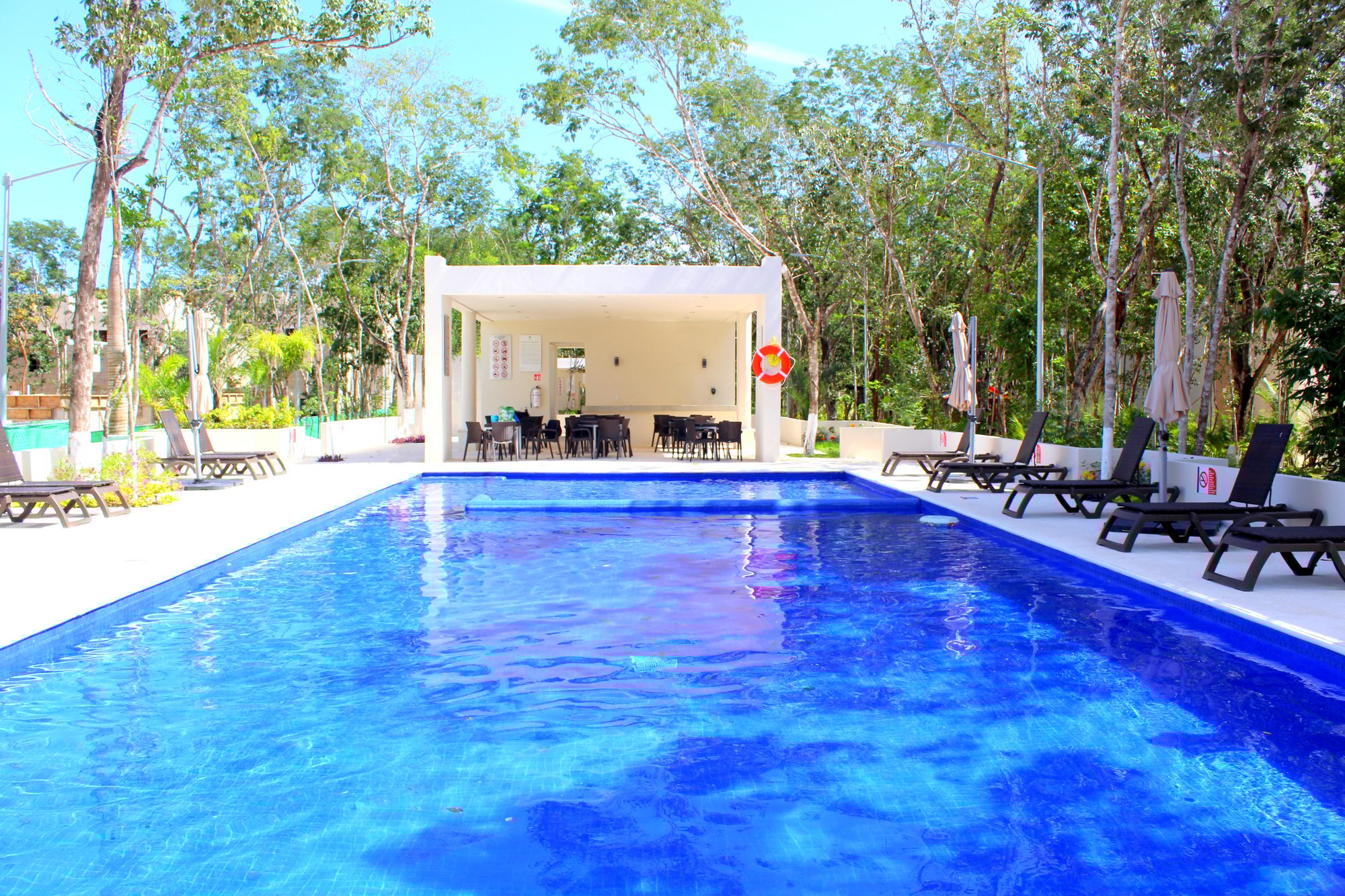 Large swimming pool with lounge chairs and covered seating area at La Selva Residences – One of five pools in this exclusive community in Playa del Carmen